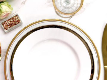 Elegant styled table setting with gold and white dishware, roses and glitter.