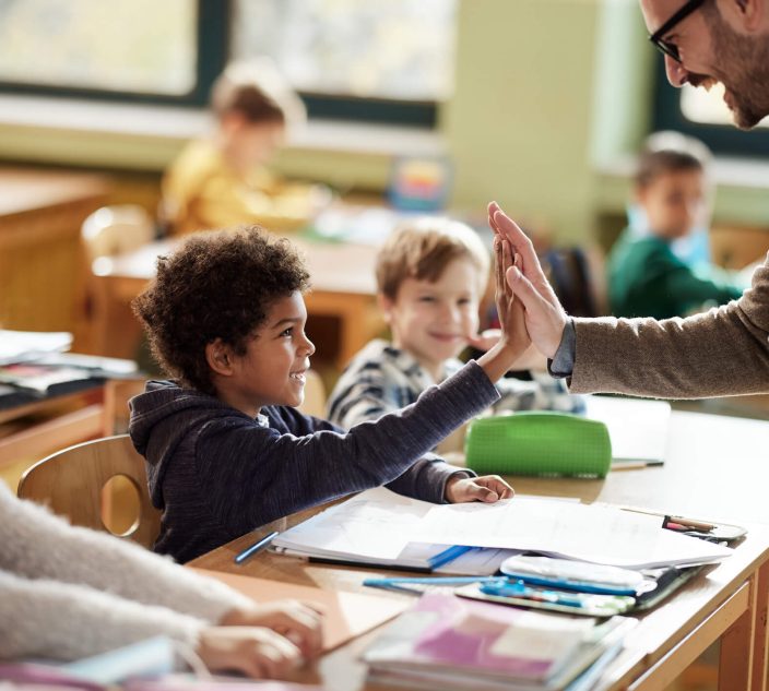 Happy teacher giving high-five to his elementary student in the classroom. Help the School to ‘Get’ Food Allergies