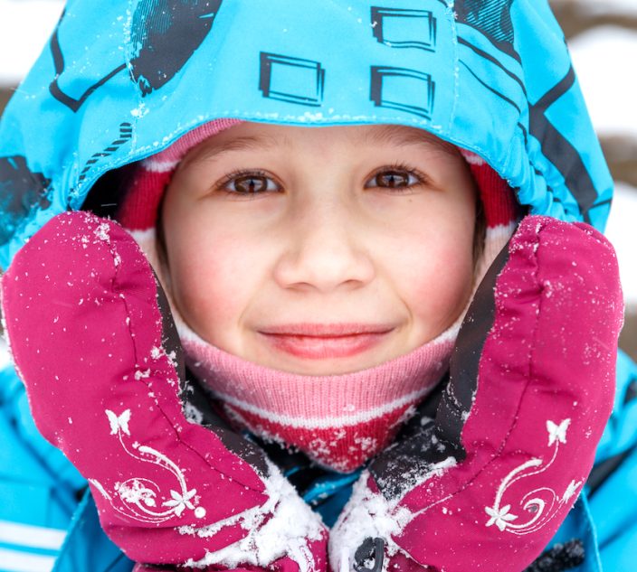 Close-up portrait of bundled up child in the snow. Cold Urticaria.
