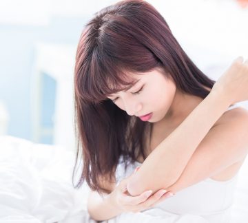 Woman looking at arm with celiac rash.