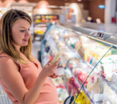 Pregnant mother decides what food to purchase at a grocery store.