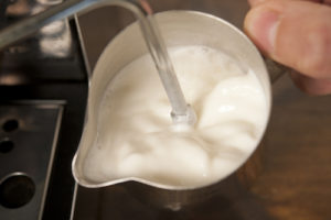 Barista froths milk.