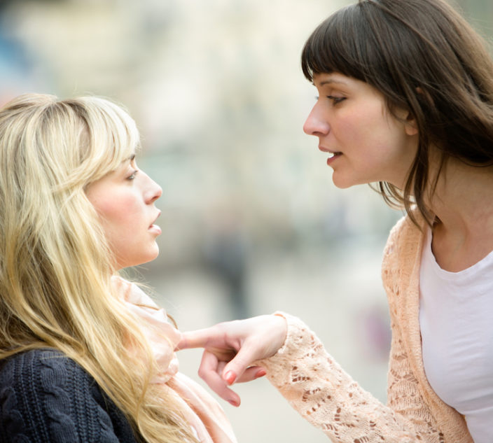 Two women talking to each other and arguing.