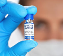 Doctor with mask holding a covid-19 vaccine.