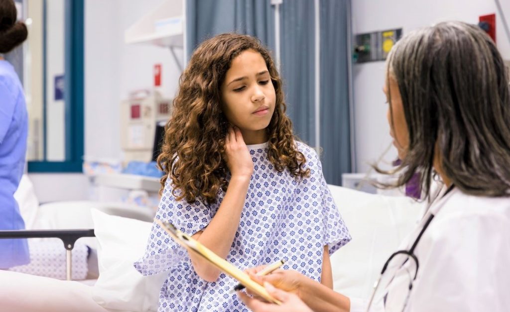 Little girl in hospital speaking with a doctor.
