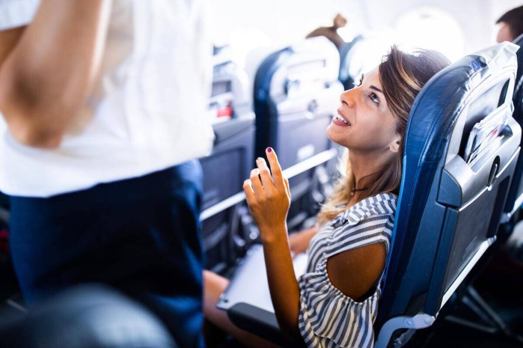 Female tourist talking to stewardess during a flight in a plane.