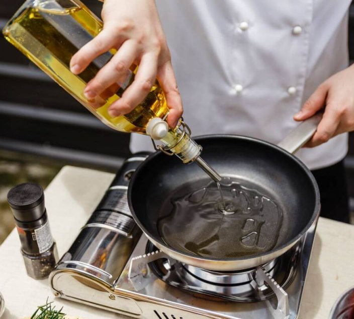 Chef cooking in a kitchen with peanut oil. Peanut oil allergy.