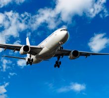 jet airplane landing in bright cloudy sky, panoramic frame