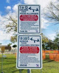 An bilingual allergy awareness park sign.